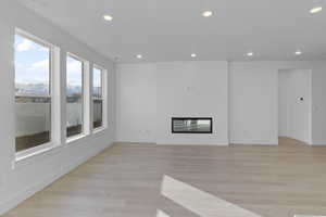 Unfurnished living room with a glass covered fireplace, light wood-style floors, and recessed lighting