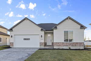 View of front facade featuring concrete driveway, a front lawn, brick siding, and an attached garage