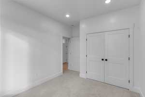 Unfurnished bedroom featuring light colored carpet, a closet, and recessed lighting