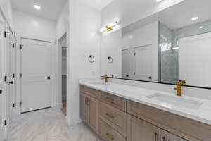 Full bathroom featuring double vanity, a marble finish shower, recessed lighting, light marble finish flooring, and a walk in closet