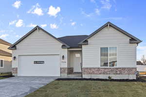 View of front of property featuring driveway, a front yard, an attached garage, and brick siding
