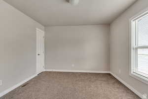 Unfurnished room featuring baseboards and light carpet