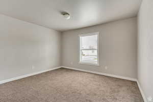 Empty room with light colored carpet and baseboards