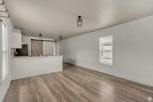 Unfurnished living room featuring a barn door and light wood-style flooring