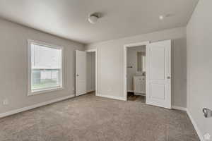 Unfurnished bedroom featuring light colored carpet and ensuite bath