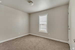 Empty room featuring baseboards and light colored carpet