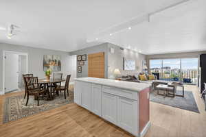 Kitchen featuring light wood finished floors, open floor plan, recessed lighting, light stone counters, and white cabinetry