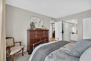 Bedroom featuring light carpet and multiple closets