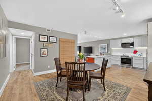 Dining area with track lighting and light wood finished floors