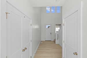 Entryway with a towering ceiling, stairway, and light wood-type flooring