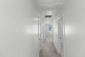 Corridor featuring light colored carpet and attic access