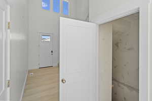 Hall featuring wood finished floors, a towering ceiling, and plenty of natural light