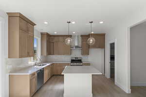 Kitchen featuring appliances with stainless steel finishes, light wood finished floors, wall chimney exhaust hood, backsplash, and recessed lighting