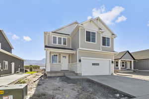 Craftsman inspired home featuring brick siding, a garage, concrete driveway, and a mountain view