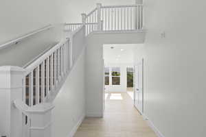 Stairs featuring a towering ceiling, wood finished floors, and recessed lighting