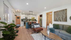 Living room with light wood-style flooring, recessed lighting, and a baseboard heating unit