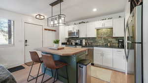 Kitchen featuring appliances with stainless steel finishes, tasteful backsplash, butcher block countertops, white cabinets, and recessed lighting