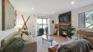 Living room featuring wood finished floors, a stone fireplace, and recessed lighting