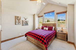 Carpeted bedroom featuring a mountain view, lofted ceiling, ceiling fan, and a textured ceiling