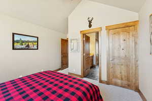 Bedroom featuring connected bathroom, carpet flooring, and high vaulted ceiling
