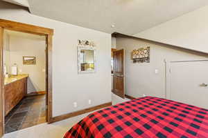 Bedroom with dark colored carpet, a textured ceiling, and ensuite bathroom