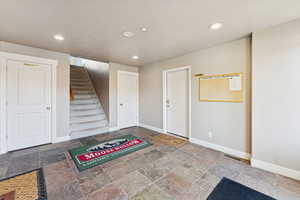 Foyer entrance with recessed lighting, stone tile floors, and stairway