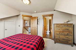 Bedroom featuring carpet flooring, a textured ceiling, and ensuite bath