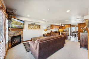 Living area with light carpet, a stone fireplace, and recessed lighting