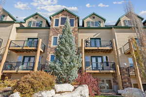 Rear view of house with stone siding and a balcony