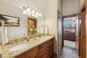 Ensuite bathroom featuring double vanity and stone tile floors