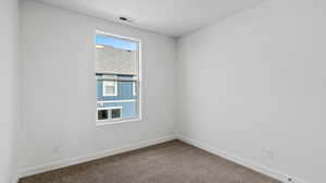 Carpeted spare room featuring baseboards
