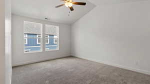 Spare room featuring light colored carpet, vaulted ceiling, and a ceiling fan
