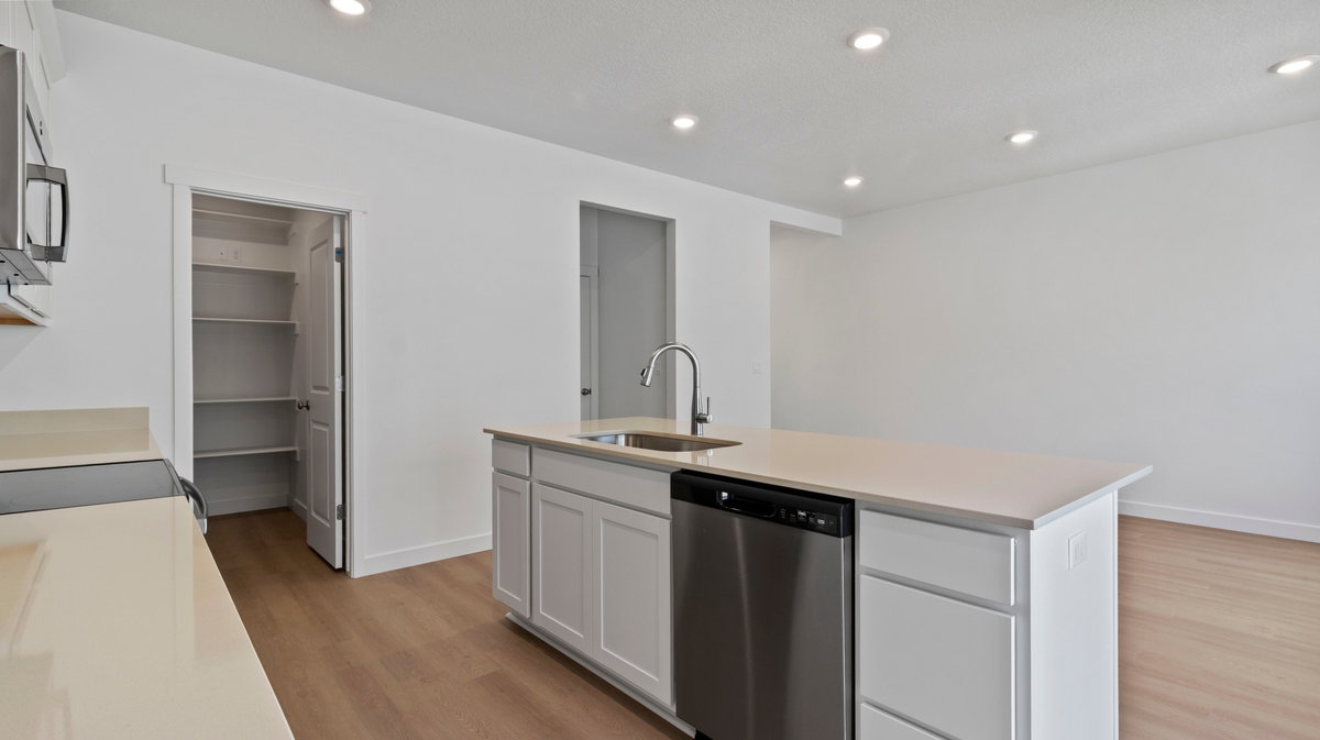 Kitchen featuring appliances with stainless steel finishes, recessed lighting, an island with sink, light wood-style floors, and white cabinets