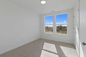 Unfurnished room featuring light carpet and baseboards