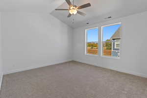 Unfurnished room with light colored carpet, vaulted ceiling, and a ceiling fan