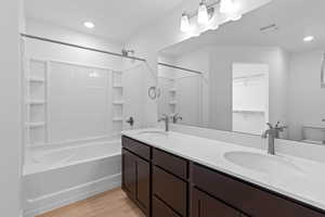 Bathroom with a walk in closet, double vanity, light wood-style flooring, shower / tub combination, and recessed lighting
