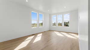 Empty room with light wood-style flooring and recessed lighting