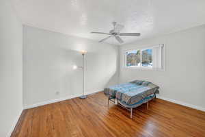 Bedroom featuring a textured ceiling, hardwood / wood-style flooring, and ceiling fan