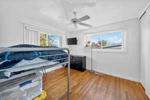 Bedroom with light wood-style flooring, a textured ceiling, a ceiling fan, and a closet
