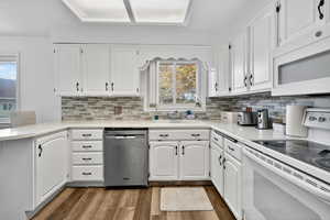 Kitchen with white appliances, a peninsula, and white cabinetry