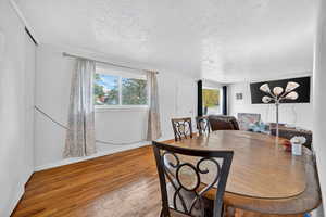 Dining area featuring wood-type flooring and a textured ceiling