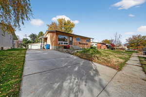 View of front of property with a front lawn, an outbuilding, brick siding, and a detached garage