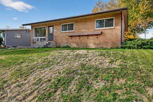 Rear view of property with brick siding and a lawn