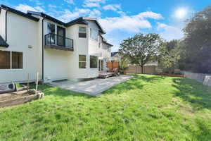 Back of house featuring a patio, a balcony, and stucco siding