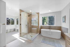 Full bath with a soaking tub, a stall shower, healthy amount of natural light, a wainscoted wall, and light colored carpet