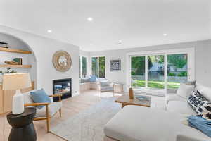 Living room featuring light wood-style flooring, a glass covered fireplace, and recessed lighting