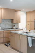 Kitchen with stainless steel dishwasher, light wood finished floors, light stone counters, recessed lighting, and light brown cabinets