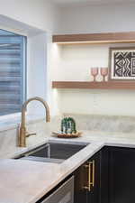 Kitchen with light stone countertops, open shelves, and dark cabinetry