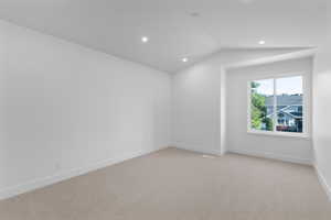 Empty room featuring lofted ceiling, light carpet, and recessed lighting