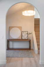 Hall with arched walkways, wood finished floors, and stairway